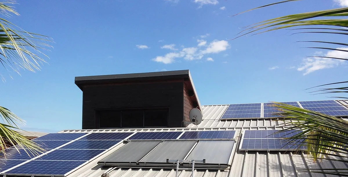Une maison de La Réunion équipée de panneaux et d'un chauffe-eau solaire, entre les cocotiers