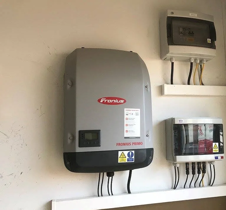 Un onduleur et ses coffrets électriques posés proprement au mur